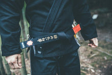 Charger l&#39;image dans la galerie, Cinturón Kanji  &quot;Un cinturón blanco que nunca se rindió&quot; - Negro con barra Roja - StockBJJ
